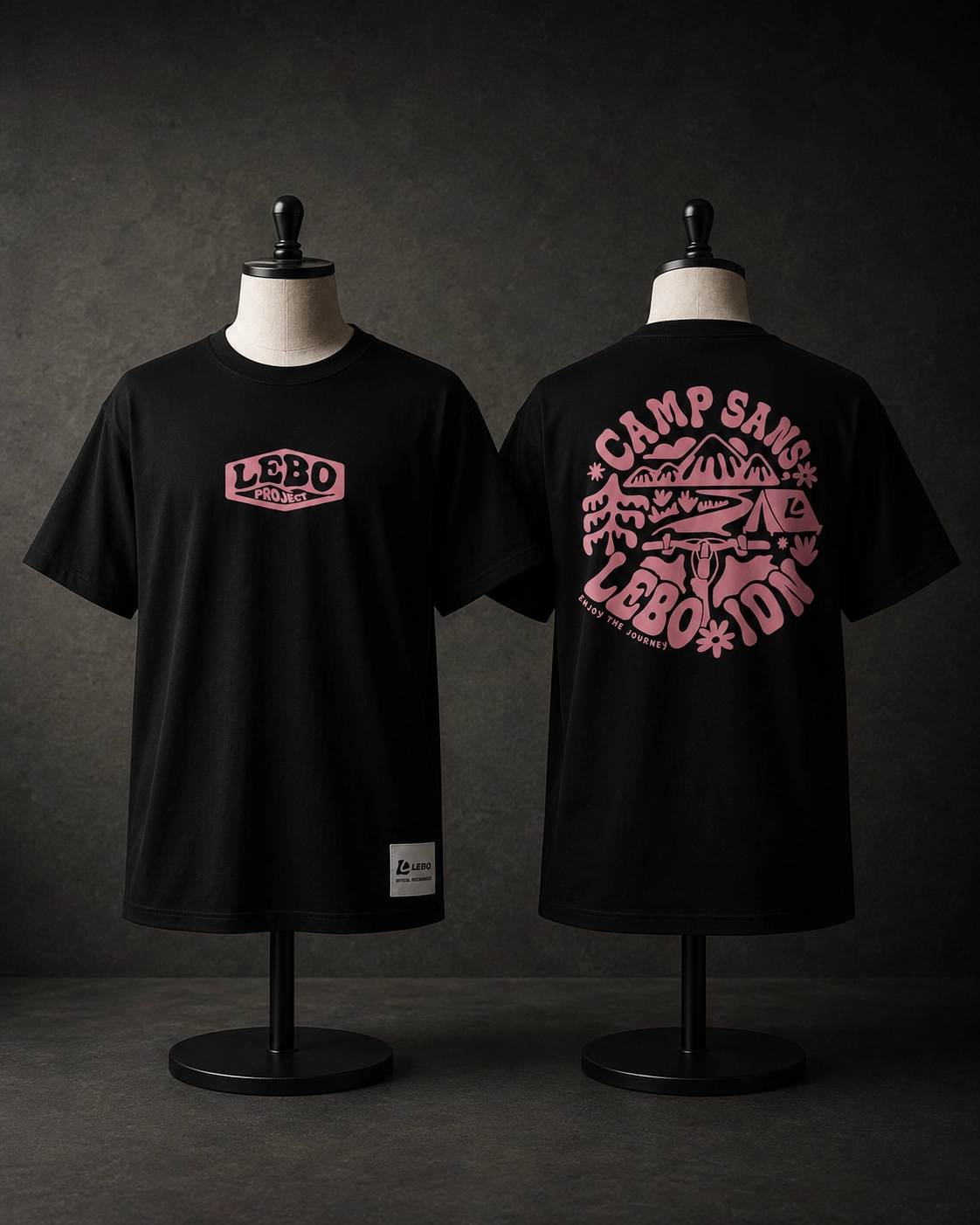 Kaos hitam merchandise Lensa Borneo dengan sablon plastisol warna pink bertema camping — ilustrasi gunung, jalur perjalanan, dan tenda di bagian belakang, dikerjakan dengan bahan katun bambu 24s anti-bakteri